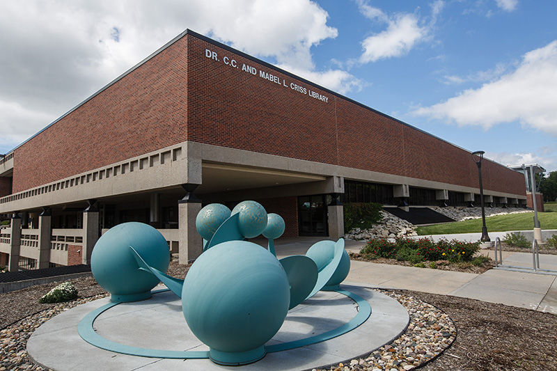a photo of criss library with a blue sphere sculpture near the front of the building