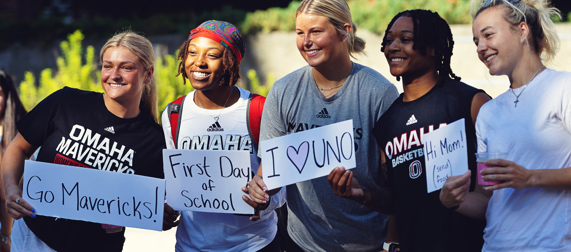 Group of students smiling holding UNO signs.