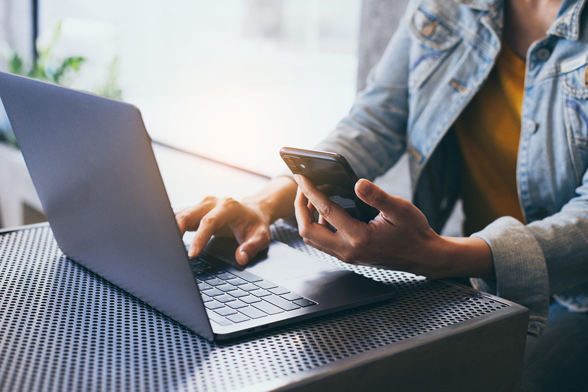 Individual at laptop while looking at computer