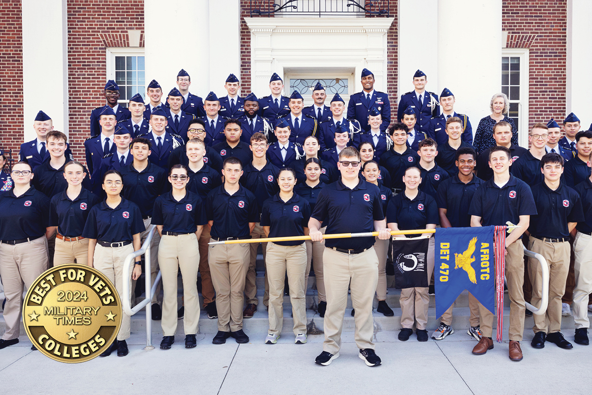 A group photo of Air Force ROTC cadets in uniform and team members in matching black shirts and khaki pants, standing in front of a brick building with white columns. The image includes a 'Best for Vets 2024 Military Times Colleges' badge in the lower-left corner.