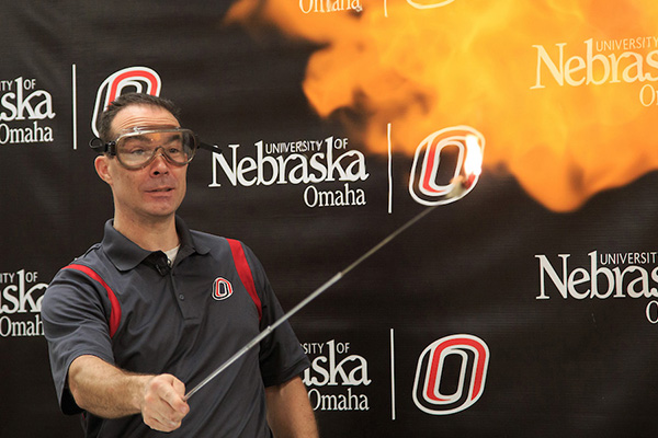 uno professor wears goggles as he demonstrates a physics experiment with fire