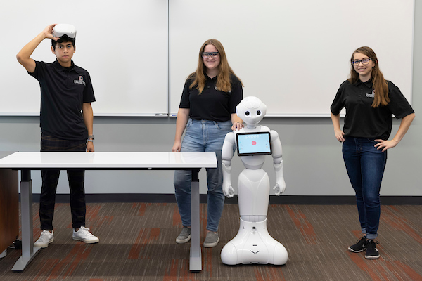 uno students stand with a robot