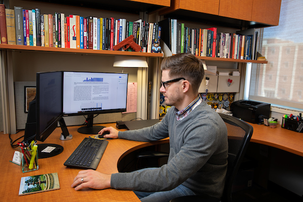 a man sits at a desk in front of laptop screen