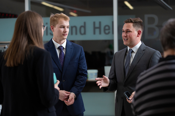 people stand in talk with each other at the cba career fair