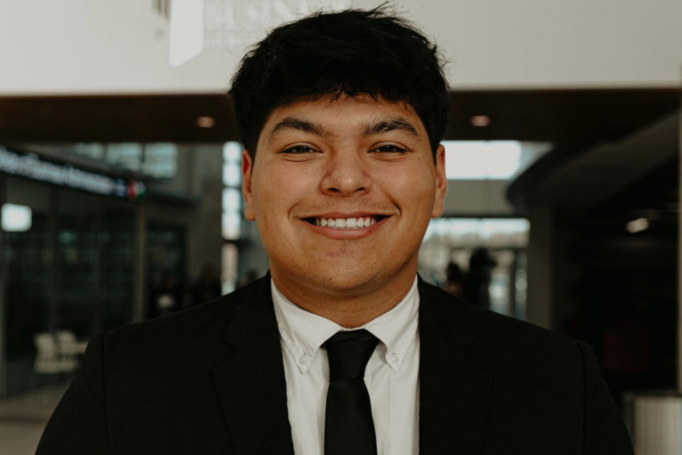 Giovanni Gomez smiles in a black suit. 