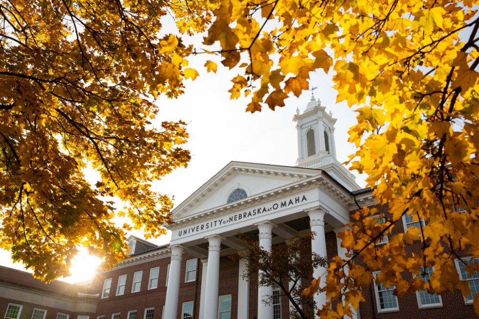 Arts and Sciences Hall is framed behind golden fall leaves. 