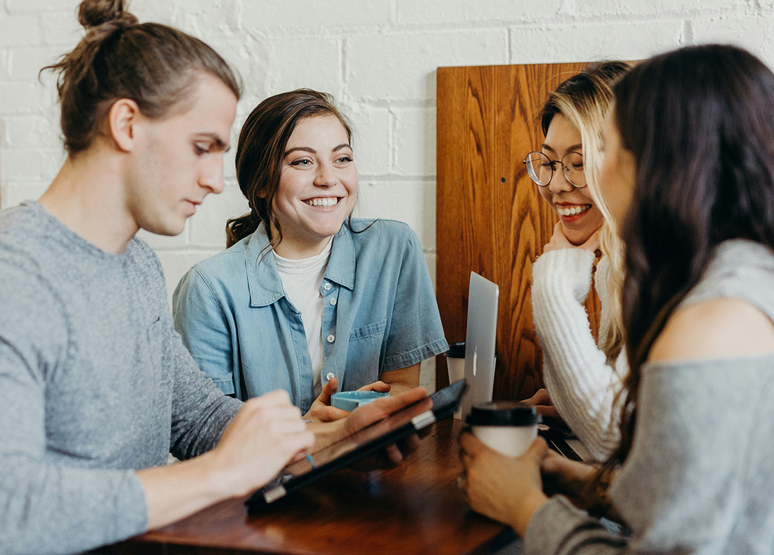 Happy young adults collaborating and working in a cafe