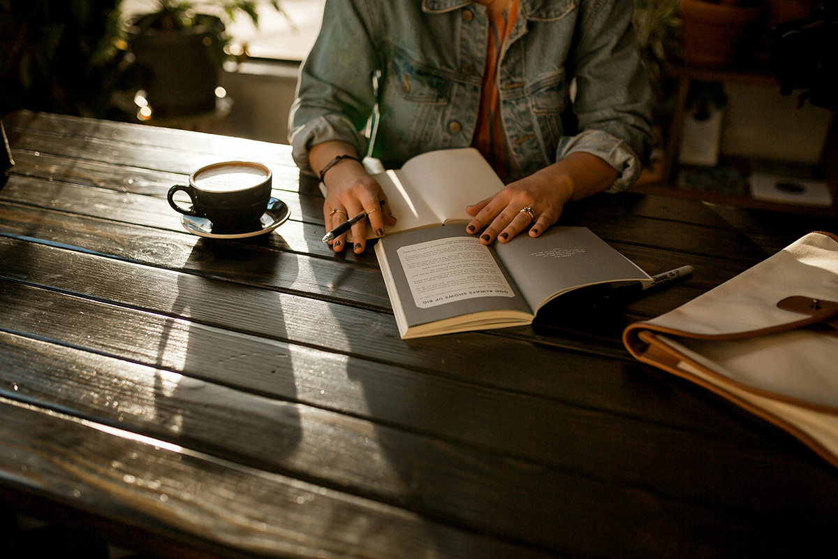 women writing ideas in a notebook at a coffee shop