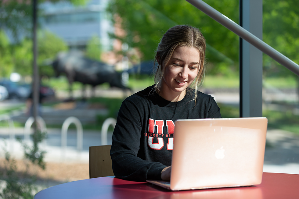 Student smiling at a laptop. 