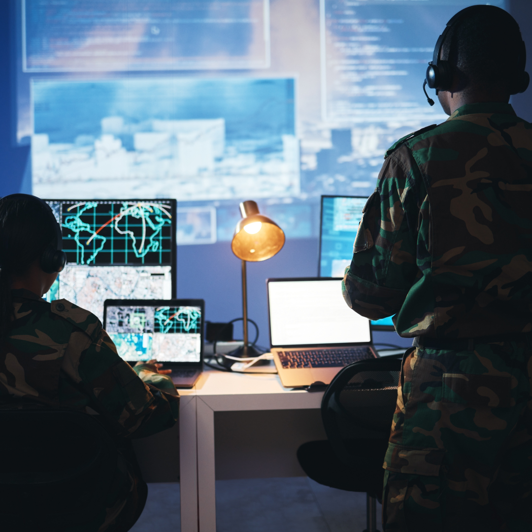 Two security professionals look at computer screens displaying maps and other security information.