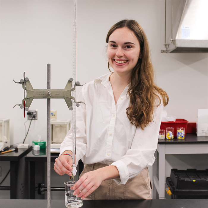 Grace stands in a chemistry lab. 