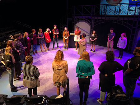 students listening to an instructor on stage