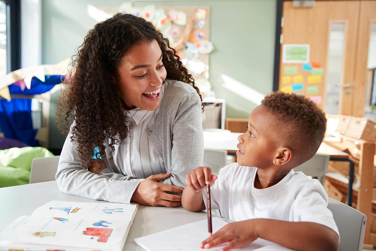 A teacher works with a young student at a table