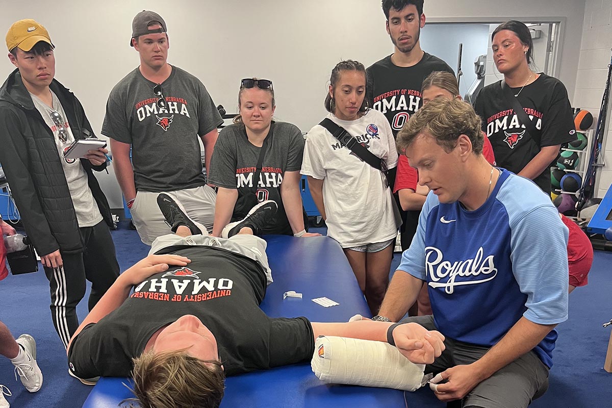 A group of people watch an athletic training in action with a patient