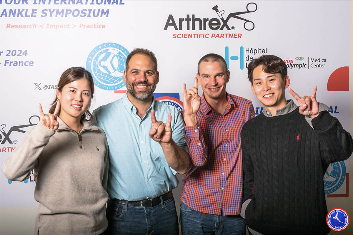 Four people pose for a photo in front of a logo backdrop