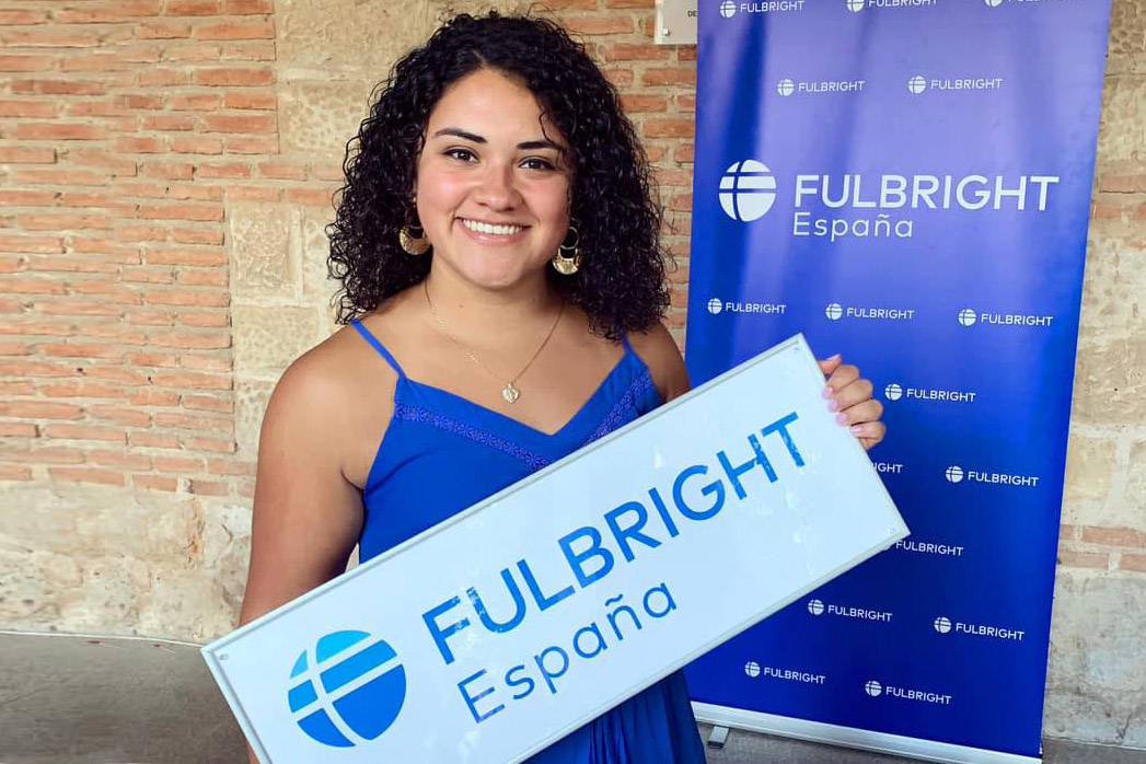 A young woman holds a sign that reads Fulbright Program