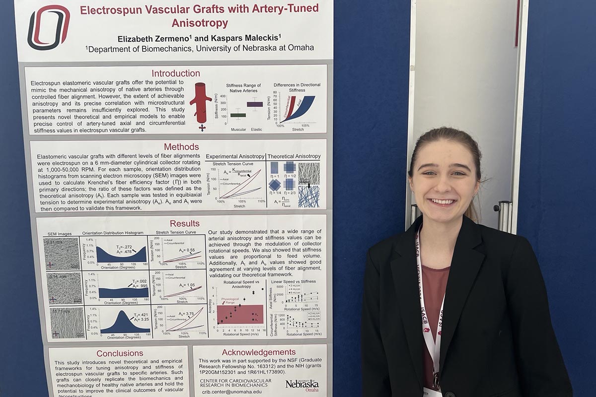 A young woman stands next to a research poster at a conference