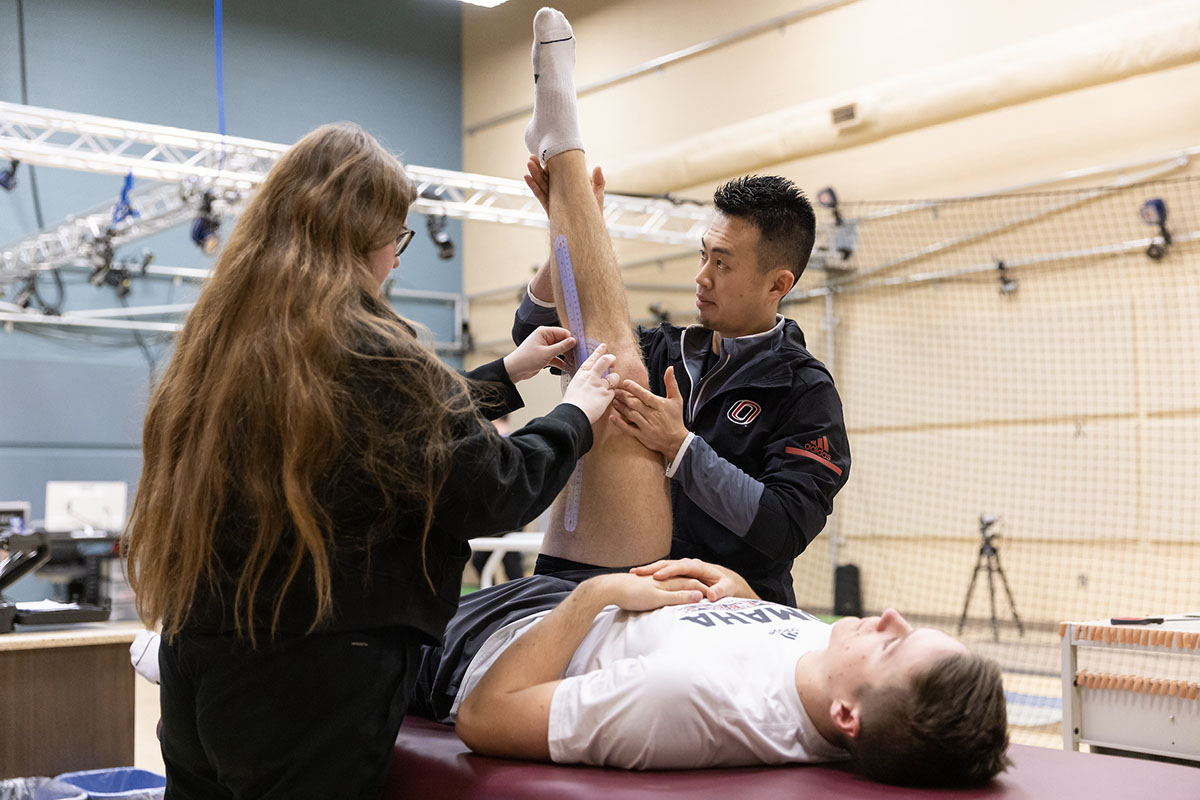 Two students work with an athlete in UNO's Pitching Lab