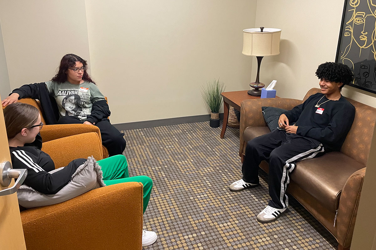 Three teens sit on couches and chairs in a counseling clinic room