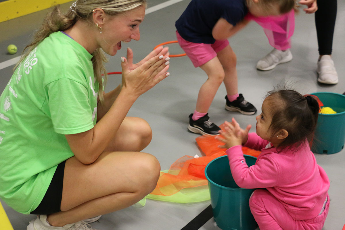 An teen volunteers claps with a young child