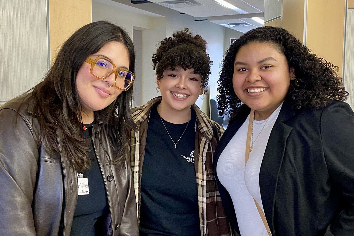 Three students pose for the camera in the Roskens Hall Atrium