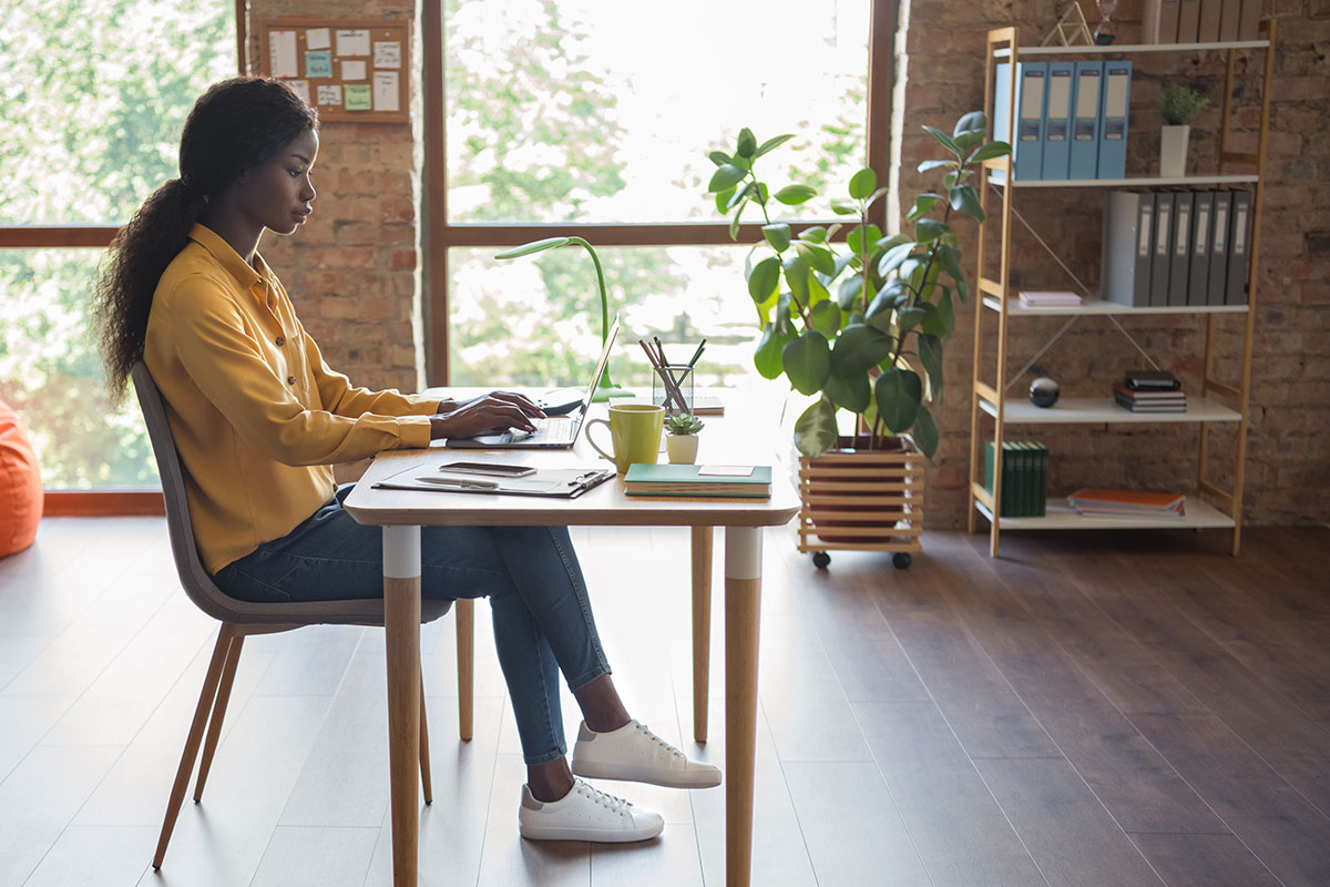 Women sits at a desk in an open office space and works on the computer