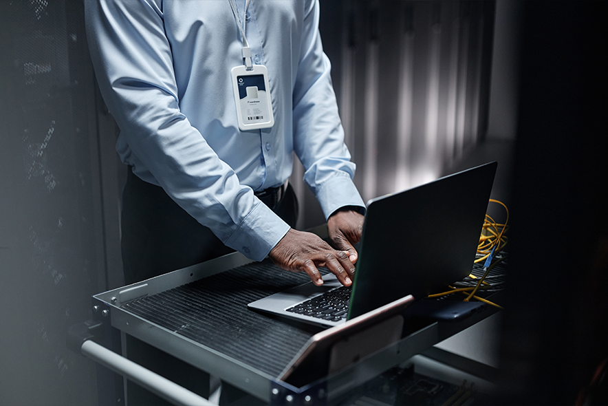 Close up of black man typing at laptop keyboard while setting up network in server room, copy space.