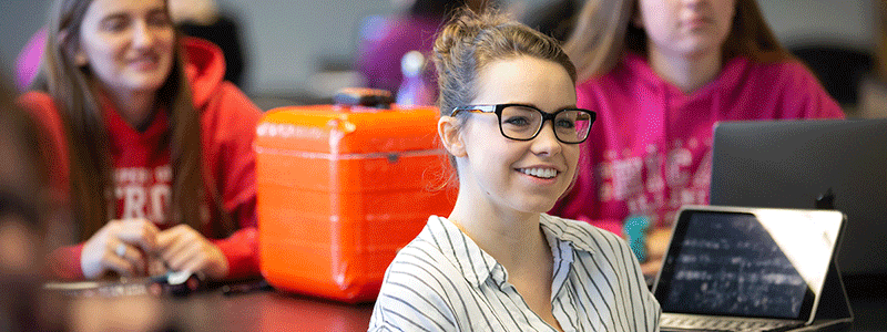 a women student smiles as she listens to her instructor