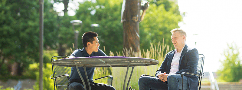 two people sit at a table and talk