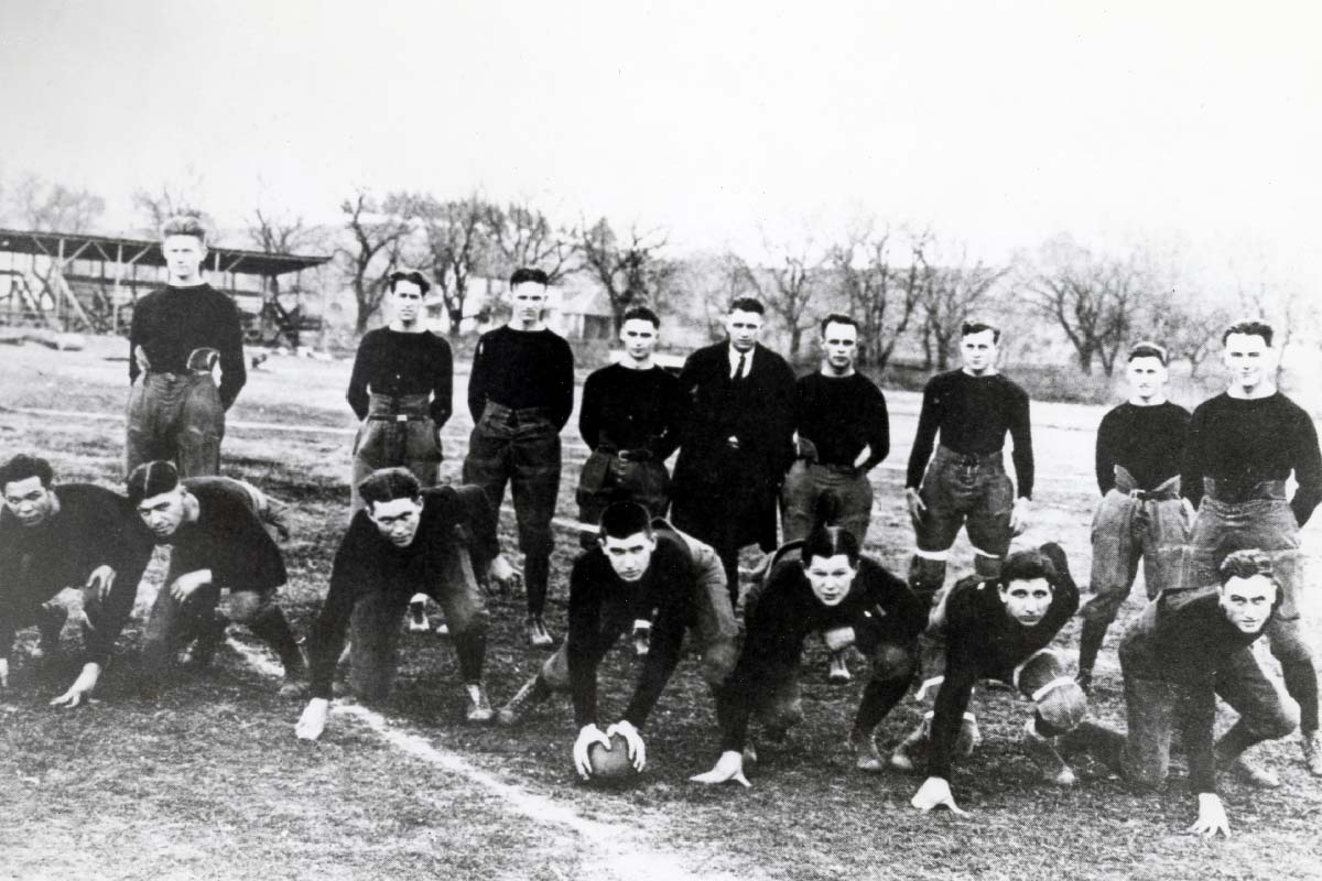 a black and white photo of a football from the 1930s; young men in football uniforms standing in rows