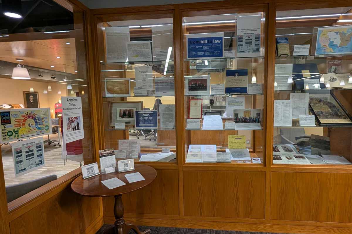 wooden and glass shelves with photos, clippings, and other ephemera about american civics  