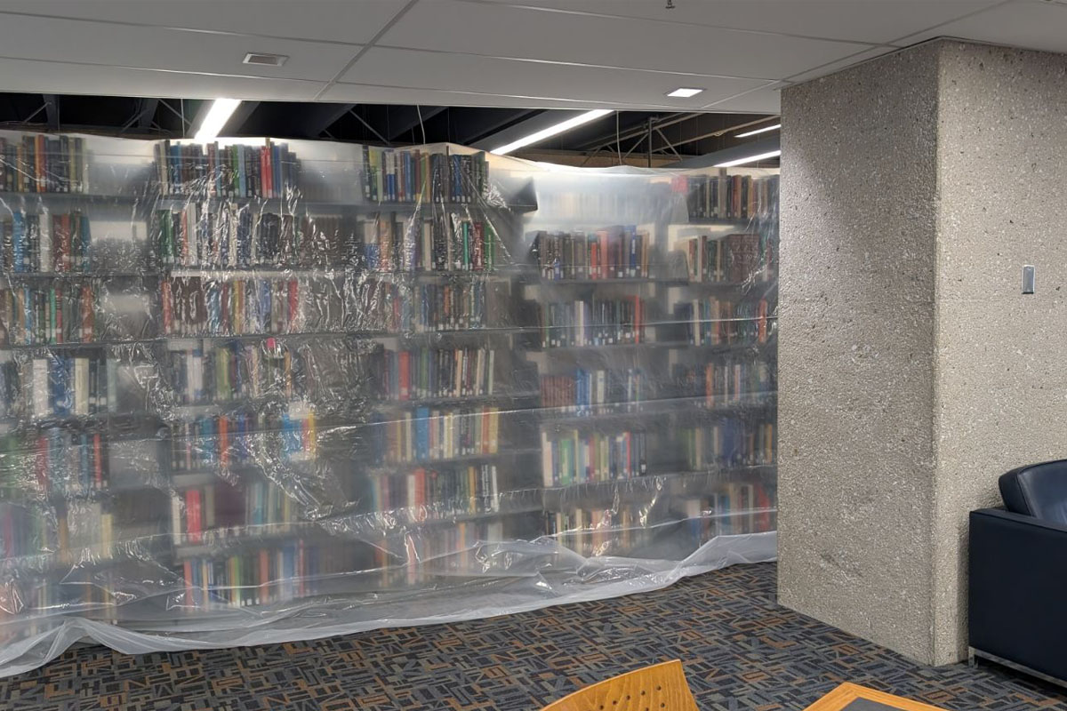 Stacks of books in a library. The stacks are covered with a sheet of plastic.