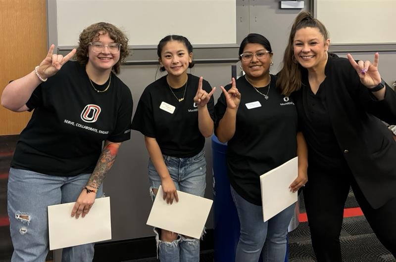 3 student workers for DASH and Rachel Jensen throwing up the mavericks on their hands and smiling for the photo