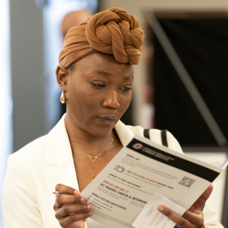 woman in a brown hesdwrap looking at a printed brochure