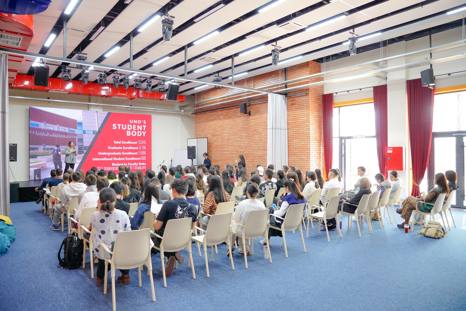 students sit in an open space facing a presentation about UNO