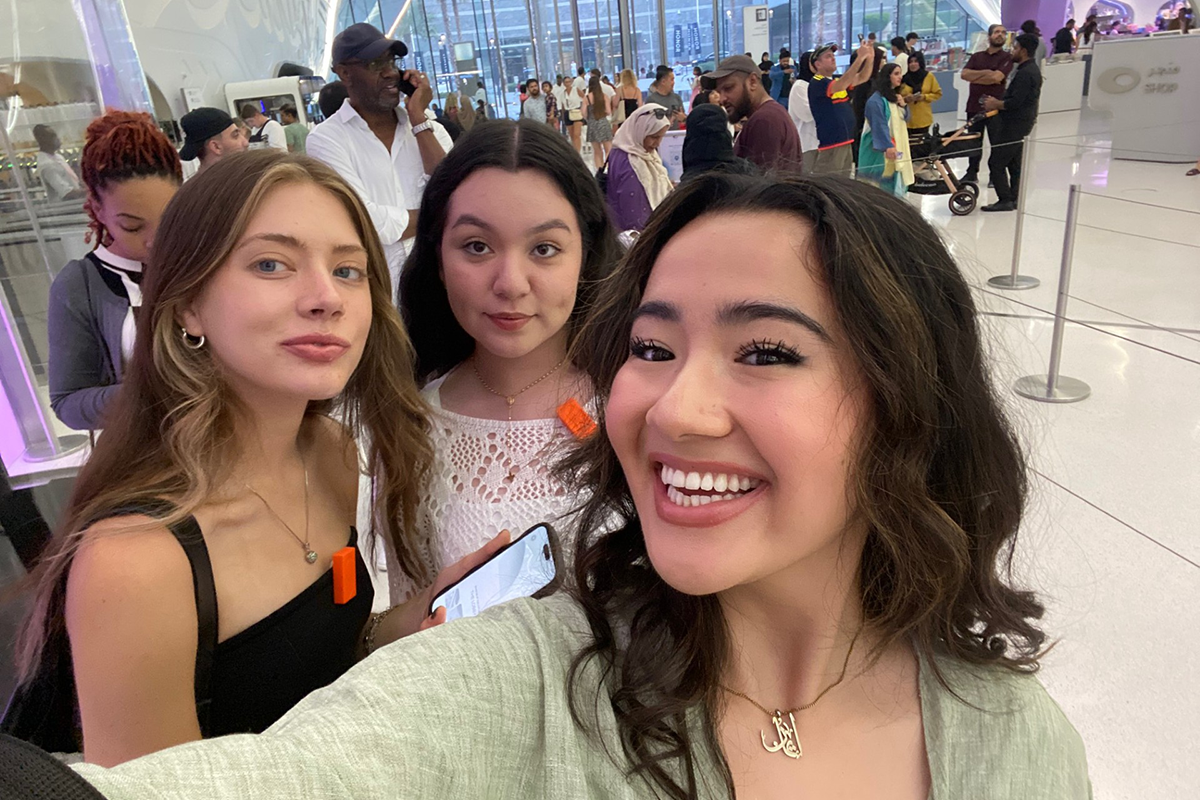 Three young women smile for a selfie indoors