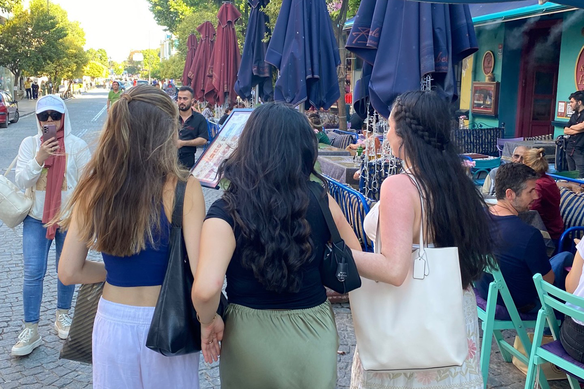 Three young woman walkng along a sidewalk, viewed from behind