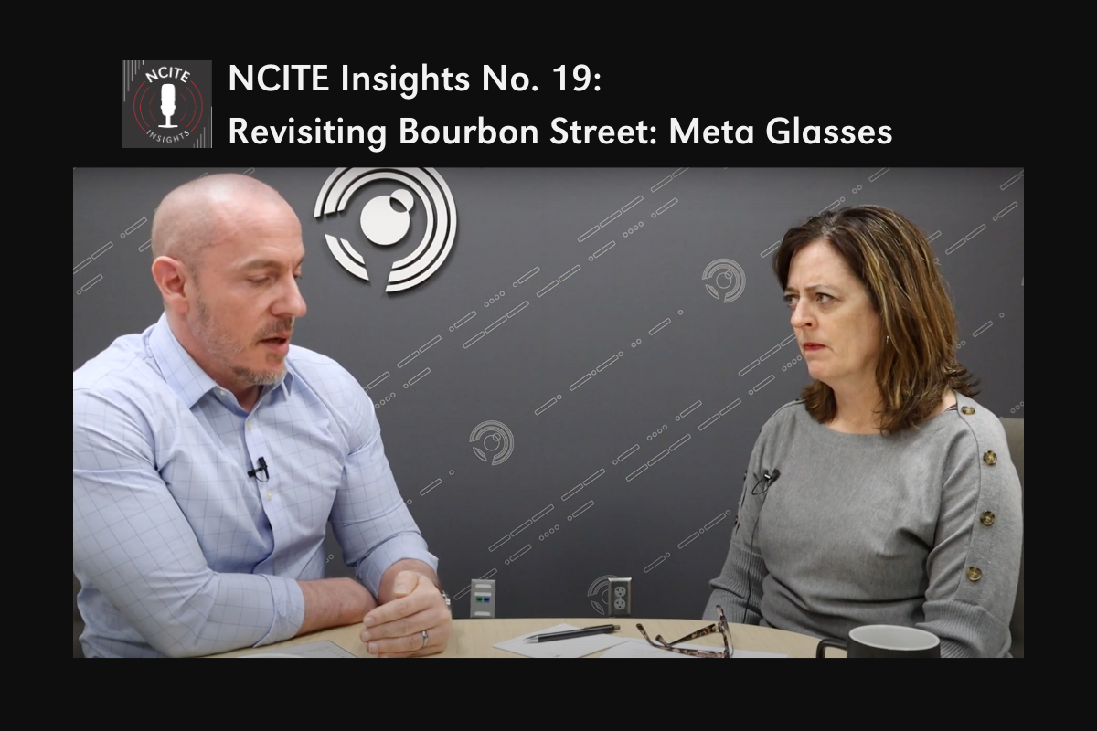 A podcast studio setup with two people seated at a table. On the left, a man wearing a light blue button-up shirt gestures with his hands while speaking. On the right, a woman in a gray sweater with button details on the shoulders listens intently, her hands folded. Between them is a table with papers, a pen, glasses, and a coffee mug. The backdrop features a dark gray wall with a patterned design and the NCITE Insights logo, which includes a microphone graphic. The text reads, "NCITE Insights No. 19: Revisiting Bourbon Street: Meta Glasses."