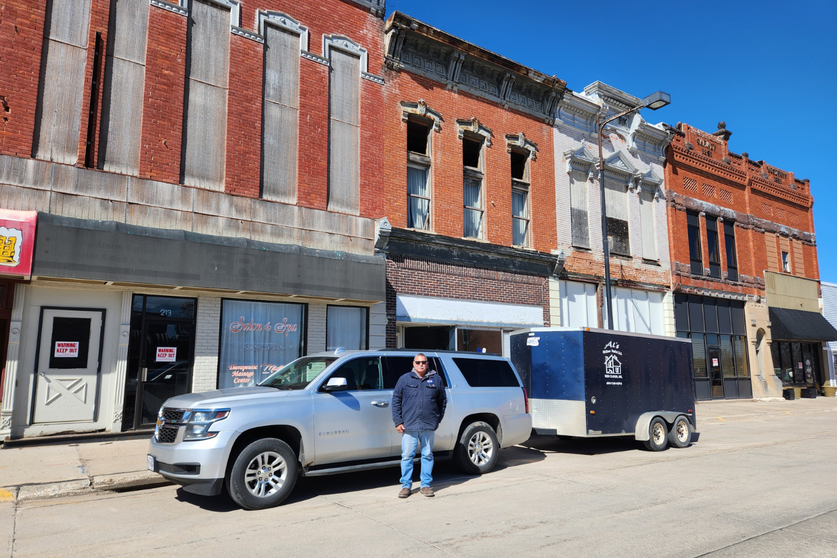 Al stands by his truck and trailer in front of a row of businesses housed in old buildings. Al's company renovated these buildings.
