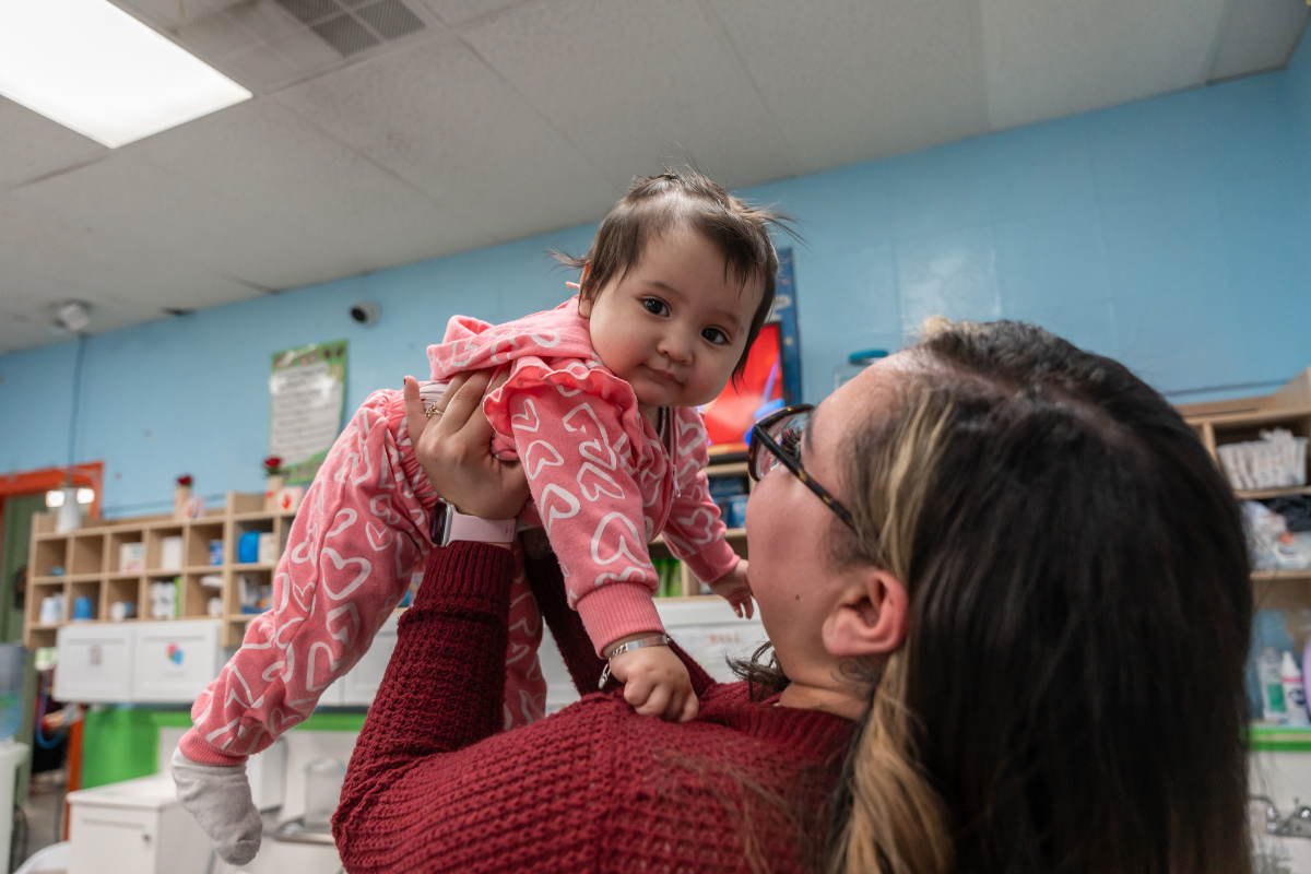Brenda Hernandez, a staff member at Patty's Childcare Center, lifts her young daughter in the air
