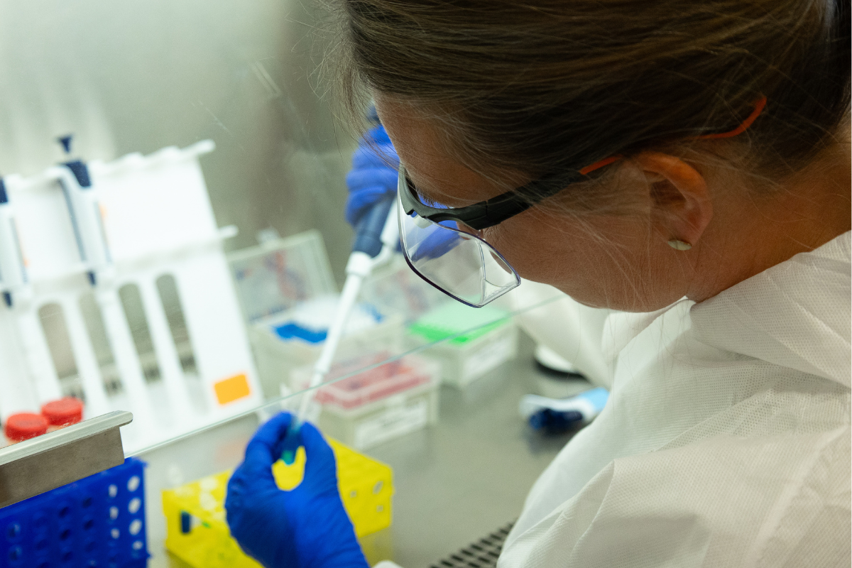 Bernhard faces away from the camera. She is in a lab holding a dropper inside a tube with a chemical solution.