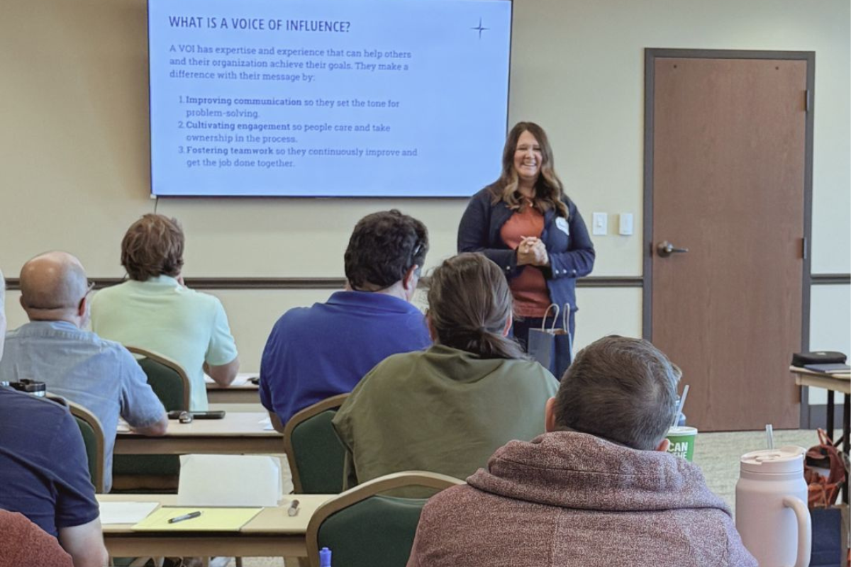 Andrea Wenburg stands in front of a PowerPoint, talking to a classroom full of people.