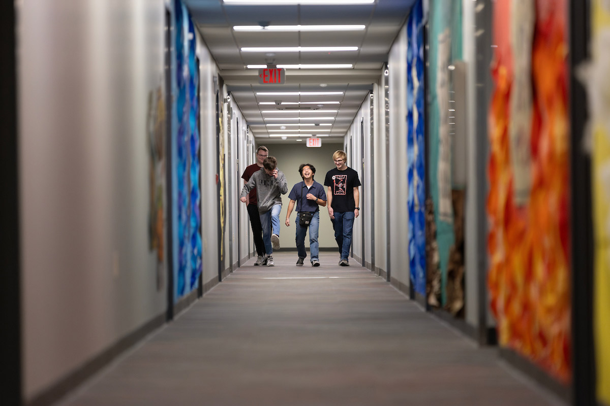 The four roommates can be seen from the end of the hallway in their dorm building. 