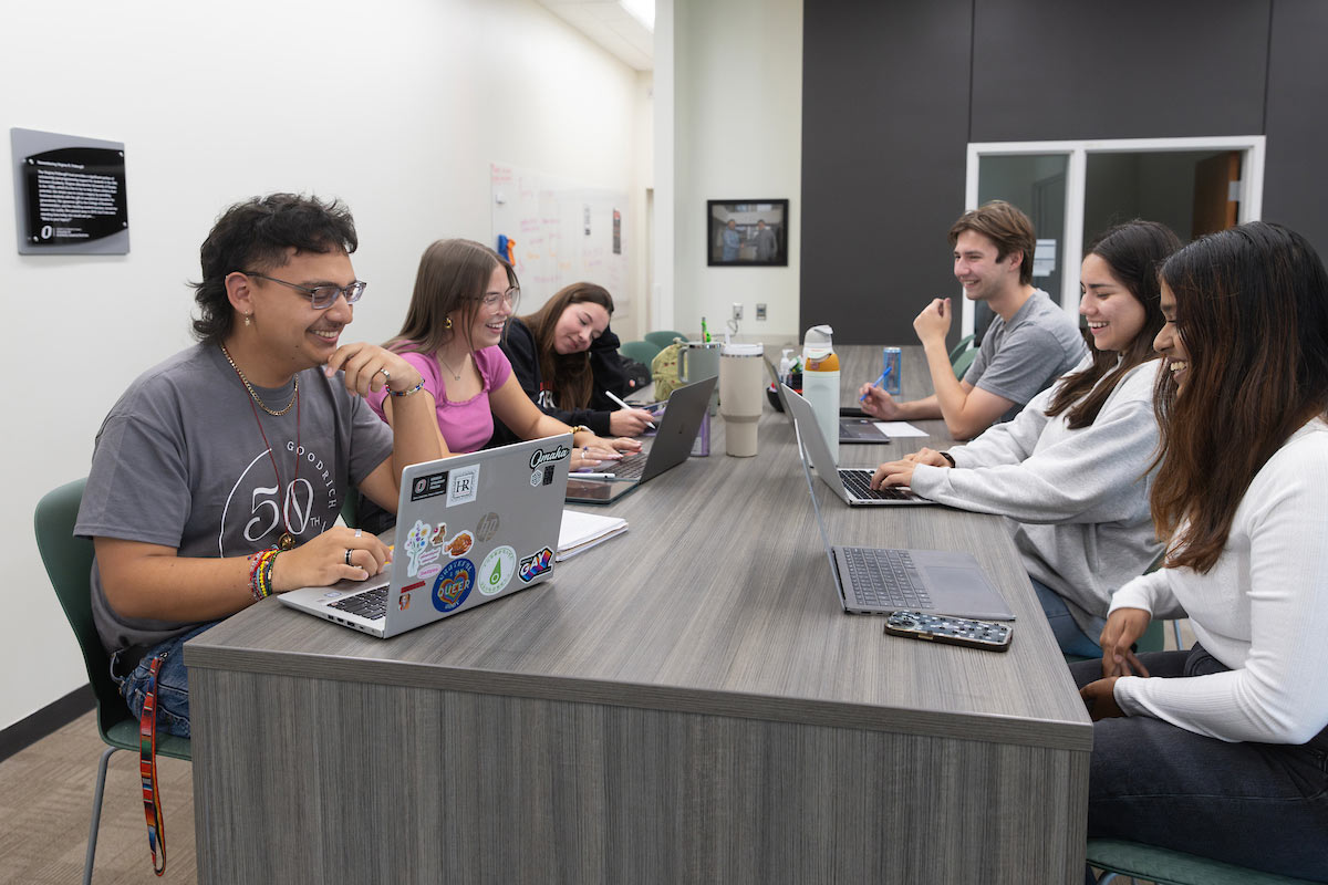 A group of students, including Jerry Brito-Mendoza, smile and work on their laptops at a study table in a collaborative learning space at the University of Nebraska at Omaha.