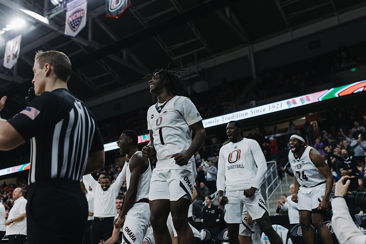 Omaha Men's Basketball players celebrate on the sidelines.