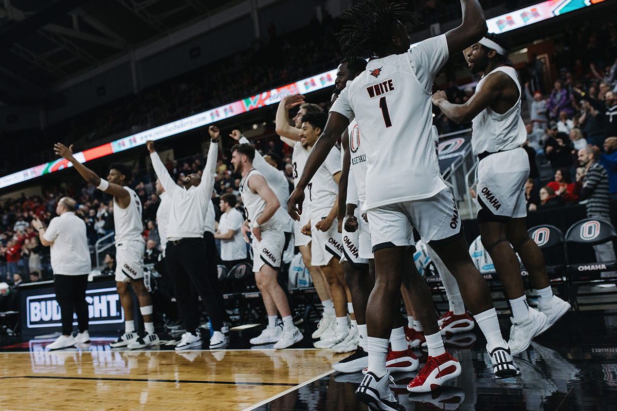 Omaha Men's Basketball players celebrate on the sidelines.