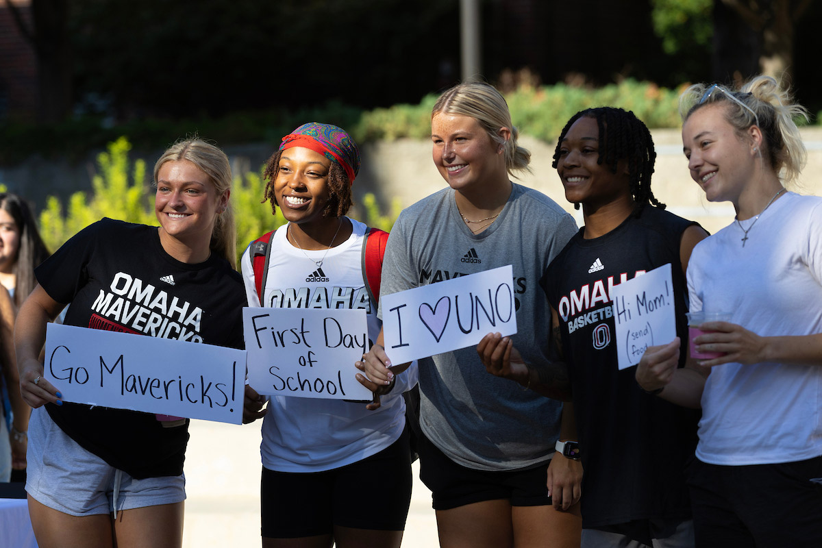 Students pose with handwritten signs on the first day of class.