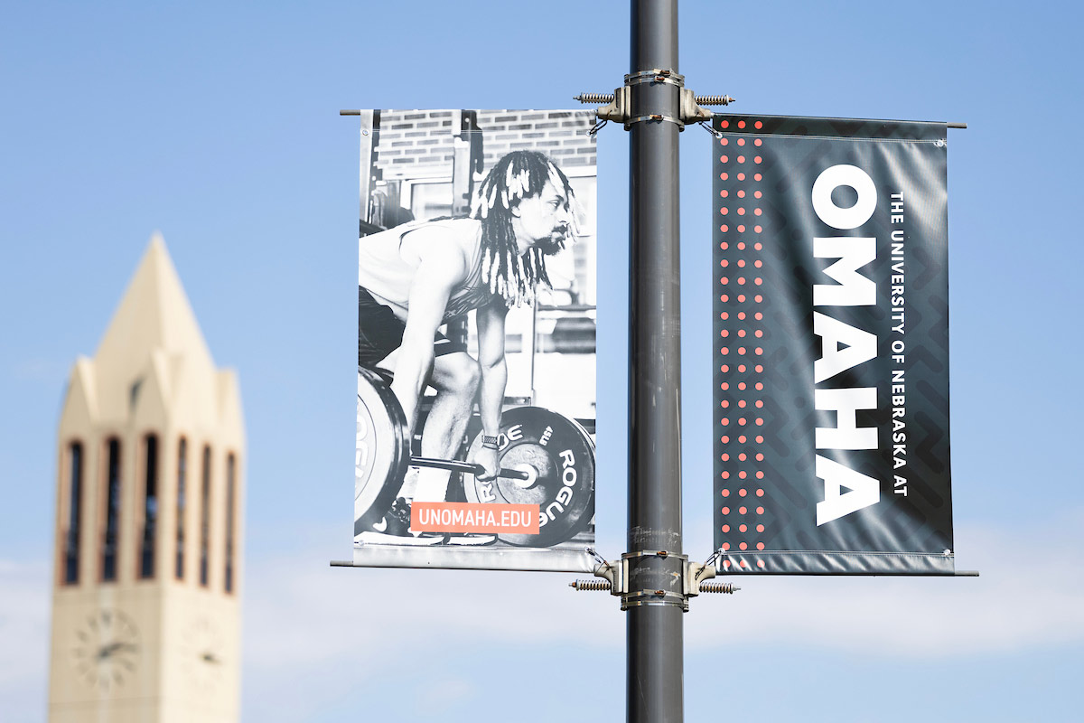 A uno banner on a pole with the campanile in the background.