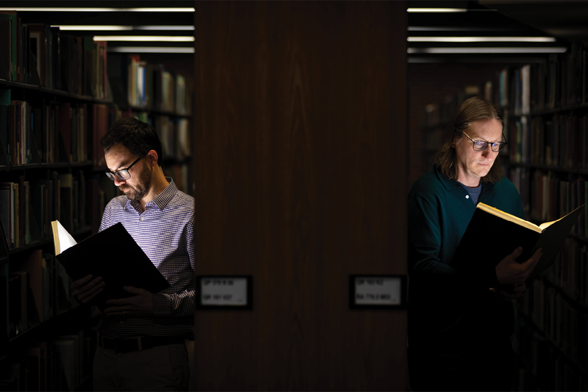 students holding books in library aisles