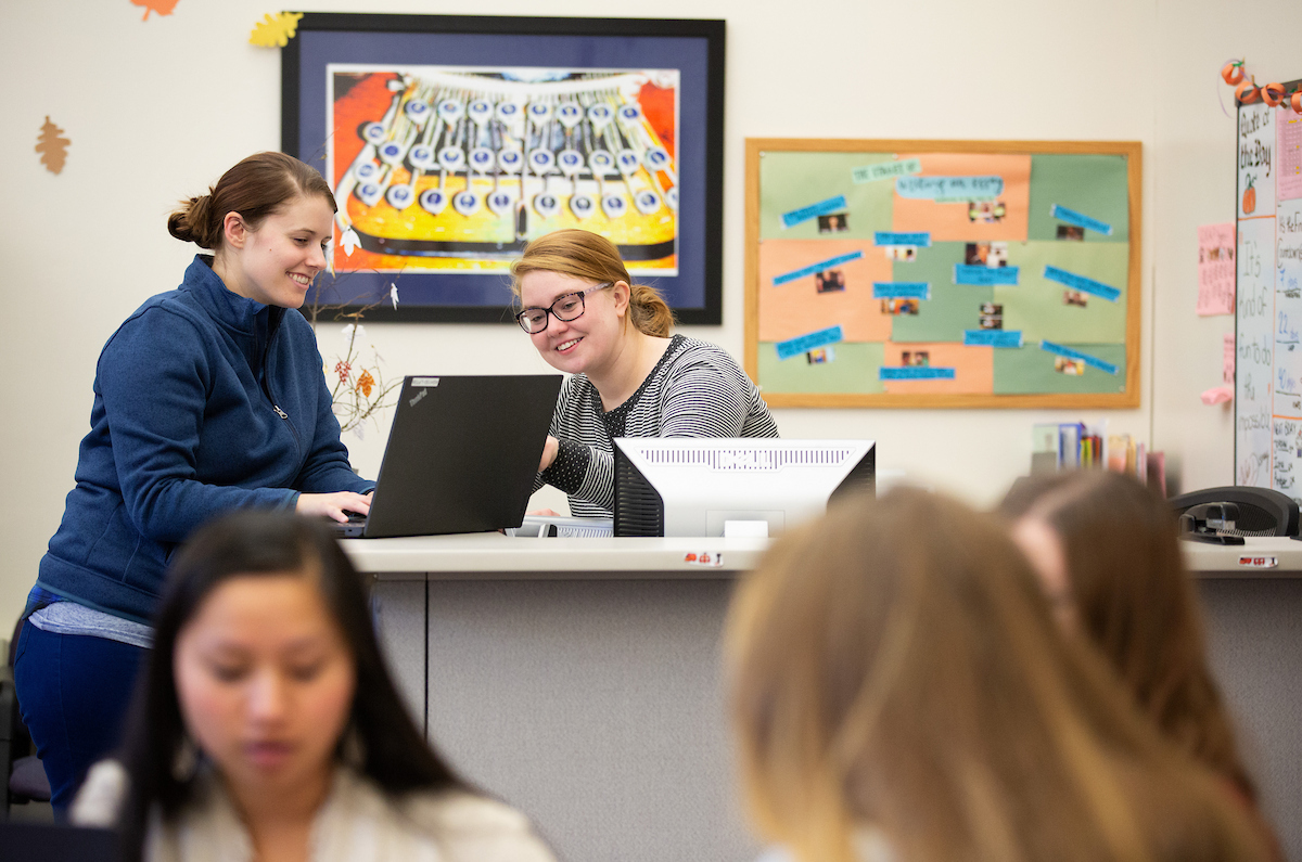 Writing Center female staff and female student reviewing screen of a laptop in the UNO writing center and smiling